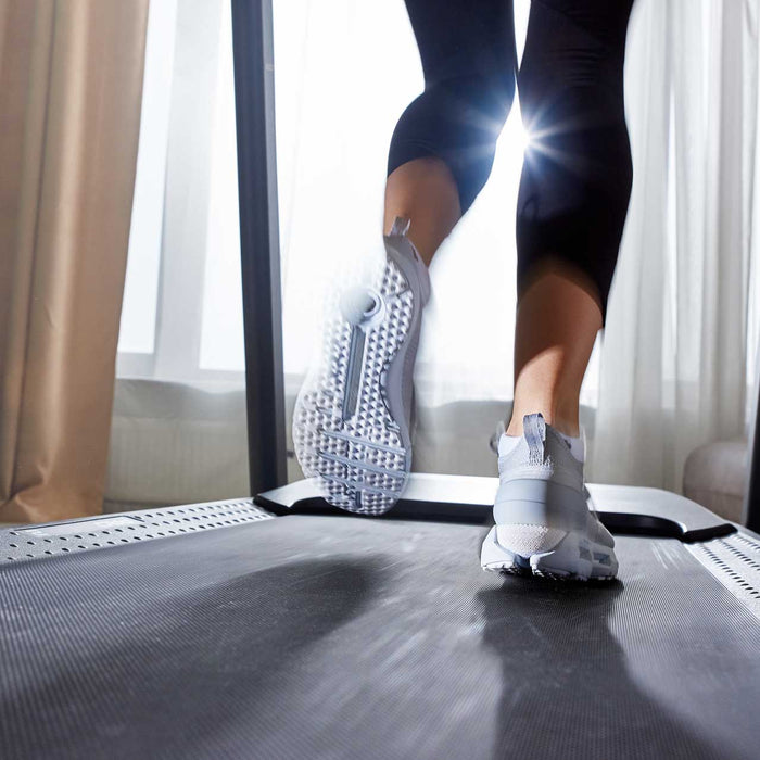 Legs of a girl in sneakers who runs on a treadmill.